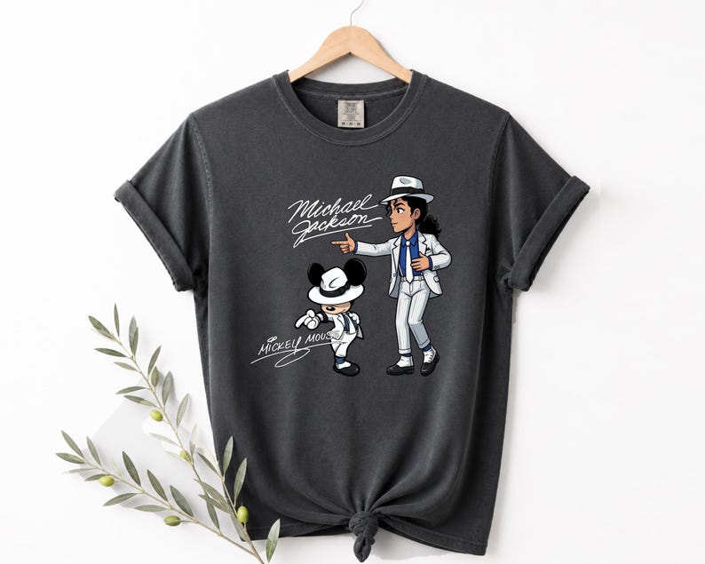 May include: Dark gray t-shirt featuring a cartoon illustration of Michael Jackson and Mickey Mouse in matching outfits. The text "Michael Jackson" and "Mickey Mouse" are written in a cursive font.