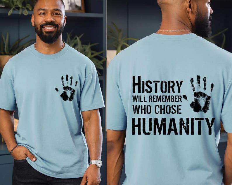 May include: Light blue t-shirt with a black handprint on the front and back. The back of the shirt features the text "History Will Remember Who Chose Humanity" in a bold, black font.