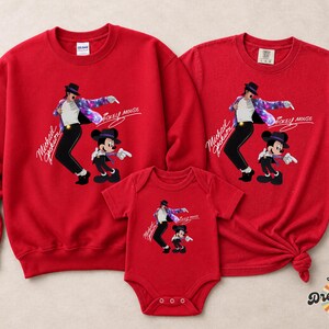 Puede incluir: Conjunto de ropa a juego para la familia, de color rojo, con un gr&aacute;fico de Michael Jackson y Mickey Mouse. El conjunto incluye una sudadera, una camiseta y un body para beb&eacute;. El texto "Michael Jackson" y "Mickey Mouse" est&aacute; impreso.