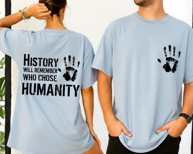 May include: Light blue t-shirts with black handprint graphics. One shirt has a handprint on the front and the other has a handprint and the text "History will remember who chose humanity" on the back.