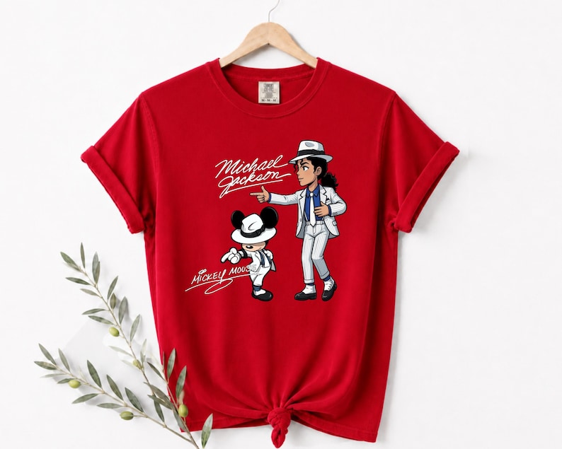May include: A red t-shirt featuring a cartoon illustration of Michael Jackson and Mickey Mouse in matching white suits and hats. The text "Michael Jackson" and "Mickey Mouse" are written in a cursive font.