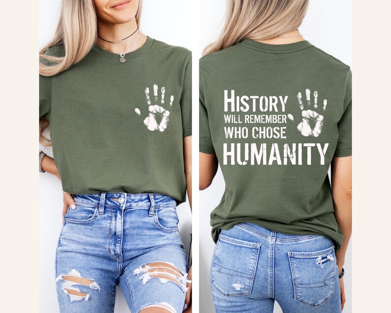 May include: Olive green t-shirt with a white handprint on the front and the text "History will remember who chose humanity" on the back. The shirt is made of a soft material and has a classic crew neck design.