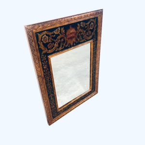 May include: Ornate rectangular mirror with a gold-colored frame and a dark teal inner border. The frame features detailed floral and scrollwork designs. The mirror's inner border has a crown and floral design.