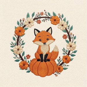 Puede incluir: Un diseño de bordado que muestra un pequeño zorro naranja sentado sobre una gran calabaza naranja. El zorro está centrado dentro de una corona circular compuesta por ramas marrones, hojas verdes y flores naranjas y crema sobre tela.