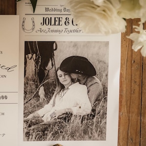 May include: Black and white wedding invitation with the text "JOLEE & C. Are Joining Together." A photograph of a couple in a field is featured on the invitation. A decorative silver belt buckle is also visible.