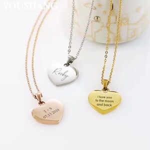 Op de afbeelding: Drie hartvormige hangerkettingen in goud, zilver en roségoud. Elke hanger heeft een andere inscriptie: "Rocky", "T+S 07.13.2010" en "I love you to the moon and back". De kettingen zitten aan fijne kettingen.
