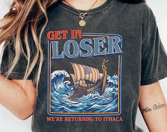 Könnte beinhalten: Dunkelgraues T-Shirt mit dem Text "GET IN LOSER" über einer Grafik eines Wikingerschiffs, das durch Wellen segelt. Der Text "WE'RE RETURNING TO ITHACA" steht darunter. Das T-Shirt hat einen Vintage-Look.
