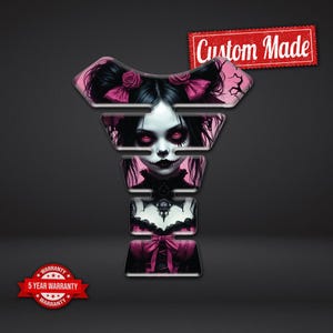 Op de afbeelding: Een op maat gemaakte motorfiets tankbeschermer met een gothic poppenontwerp. De afbeelding toont een pop met zwart haar, roze strikken en rode ogen. De tekst "Custom Made" staat in een rode banner.