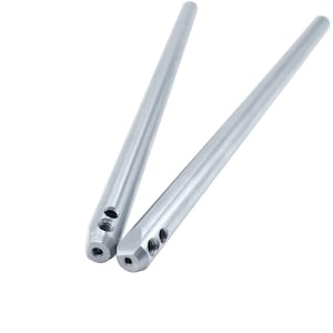 Könnte beinhalten: Zwei identische silberfarbene Metallstäbe mit glatter, zylindrischer Oberfläche. Jeder Stab verfügt über ein verjüngtes Ende mit einer einzelnen kreisförmigen Öffnung an der Spitze sowie zwei kleineren Gewindebohrungen an der Seite des verjüngten Bereichs.
