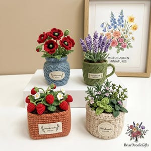 May include: Four handmade crochet miniature garden plants. The plants include red poppies in a blue vase, lavender in a green mug, strawberries in an orange basket, and a mixed plant in a beige basket. Each pot has a "Handmade with Love" tag.