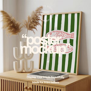 Könnte beinhalten: Ein gerahmtes Poster mit grün-weiß gestreiftem Hintergrund zeigt zwei rote Fischillustrationen. Das Poster wird auf einem Holzschrank zusammen mit einer weißen Vase mit getrockneten Pflanzen und einem dekorativen Buch ausgestellt. Der Text "poster mockup" ist auf dem Bild überlagert.