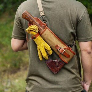 May include: Axe with a wooden handle and a canvas and leather sheath, worn over the shoulder. Includes yellow work gloves and a small leather axe head cover. The sheath has a brown leather strap and buckle.