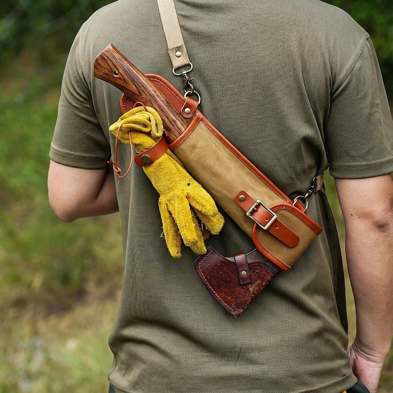 May include: Axe with a wooden handle and a canvas and leather sheath, worn over the shoulder. Includes yellow work gloves and a small leather axe head cover. The sheath has a brown leather strap and buckle.