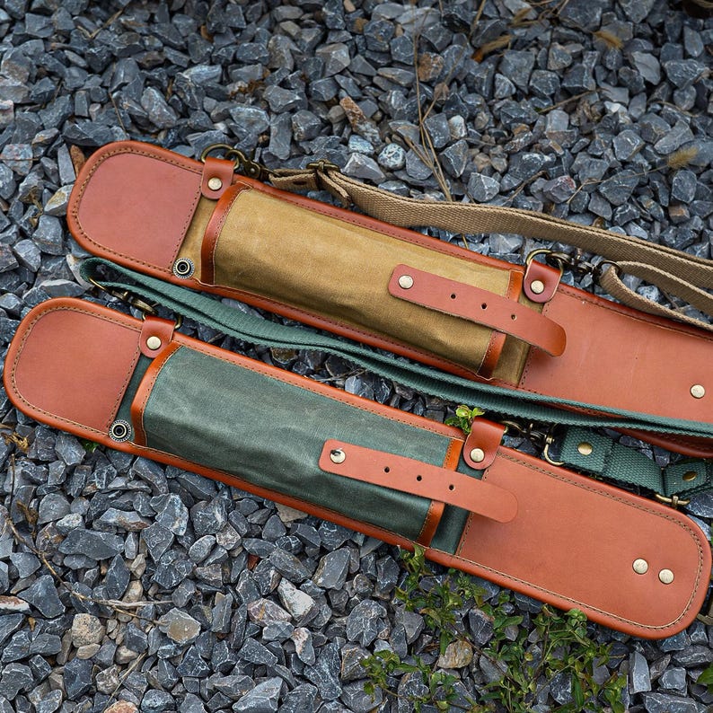 May include: Two leather and canvas cases with adjustable straps. The cases have brown leather accents and straps, with a green and tan canvas body. The cases are designed to hold long, slender objects.