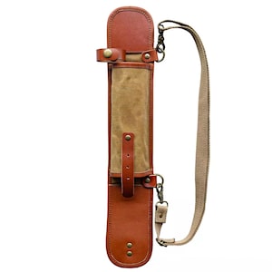 May include: A brown leather and canvas carrying case with a shoulder strap. The case has a rectangular shape with a flap closure and a tan canvas center. The shoulder strap is a light brown color and is attached with metal clasps.