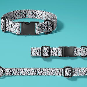 May include: Three dog collars with a penguin pattern on a teal background. The collars have black plastic buckles and metal D-rings. The penguin pattern is black, white, and light blue.