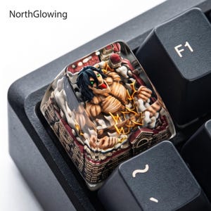 May include: A custom mechanical keyboard keycap featuring a detailed resin sculpture of a muscular, tan-skinned humanoid figure with black hair and glowing green eyes, surrounded by white smoke and miniature brown buildings.
