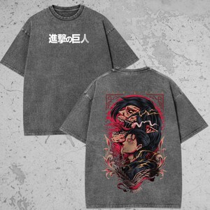 May include: A charcoal grey acid-wash t-shirt featuring the Japanese text "進撃の巨人" on the front chest. The back displays a detailed graphic illustration of a character profile layered with a skeletal titan figure, accented by red and black floral motifs.