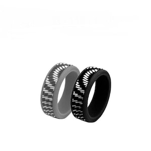 May include: Two silicone rings, one gray and one black, are displayed. Both rings feature a repeating pattern of white diagonal lines. The rings are designed for comfort and flexibility, suitable for everyday wear or active lifestyles.