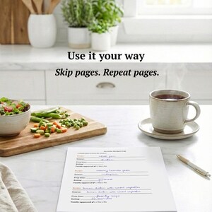 May include: A kitchen setting featuring a wooden chopping board with vegetables, a salad bowl, and a mug of tea. A recipe log and pen are on the table. The text "Use it your way. Skip pages. Repeat pages." is visible.