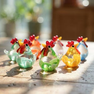 May include: A collection of colorful glass chicken figurines. Each figurine has a red comb, yellow beak, and a body in shades of green, orange, yellow, and blue. The figurines are displayed on a wooden surface.