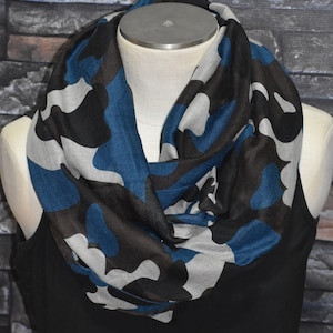 May include: A gray, black, and blue camouflage infinity scarf. The scarf is made of a soft, lightweight fabric and is perfect for adding a touch of style to any outfit.