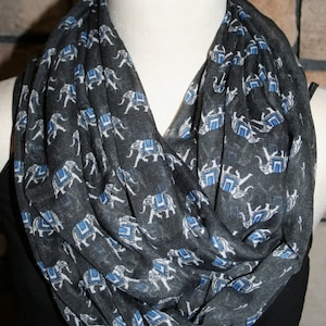 Puede incluir: Una bufanda infinita gris con un patrón repetido de elefantes blancos con acentos azules.