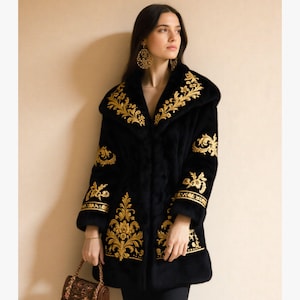 Może przedstawiać: Czarny płaszcz ze złotym haftem. Płaszcz posiada bogate złote kwiatowe wzory wzdłuż kołnierza, rękawów i dołu. Płaszcz ma kaptur i jest noszony przez osobę. Osoba nosi również złote kolczyki.