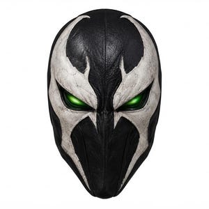 May include: A full-face mask featuring a black base with a textured white design resembling an M-shaped emblem across the forehead and eyes. The mask has two almond-shaped eye openings that glow with a bright, vibrant green light.