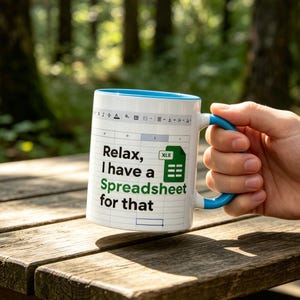 Può includere: Tazza in ceramica bianca con interno e manico blu. La tazza presenta il testo "Relax, I have a Spreadsheet for that" in nero e verde, insieme a un'icona di Excel. La tazza è tenuta sopra una superficie di legno.