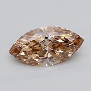 May include: A marquise-cut gemstone with a light champagne or brownish-tan hue. The stone features a faceted surface that creates a complex pattern of light reflection and refraction, resulting in a brilliant, multi-faceted appearance.