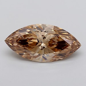 May include: A marquise-cut gemstone with a light brown, champagne-coloured hue. The stone features a faceted surface that creates a symmetrical pattern of light and dark reflections throughout its elongated, pointed oval shape.