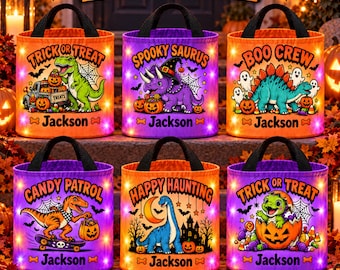 May include: Six cylindrical Halloween treat bags with black handles, each featuring a unique dinosaur illustration, pumpkins, and the name Jackson. The designs include text like Trick or Treat, Spooky Saurus, Boo Crew, Candy Patrol, and Happy Haunting.