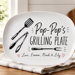 May include: White oval grilling plate with black text and illustrations. The plate reads "Pop-Pop's Grilling Plate" with images of grilling tools. The bottom of the plate says "Love, Emma, Noah & Lily" with a heart.