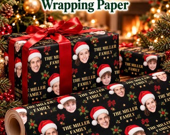 May include: Black wrapping paper featuring a repeating pattern of various people wearing Santa hats, the text The Miller Family, and small red and green holly accents. A large red satin ribbon is tied around a gift box wrapped in this paper.