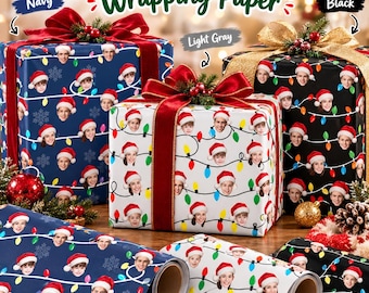 May include: Custom face wrapping paper in navy, light gray, and black, featuring a repeating pattern of faces wearing Santa hats connected by colorful Christmas light strings. The paper is shown on three wrapped gift boxes with bows.