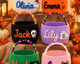 May include: Six round rope baskets in white, orange, black, purple, green, and pink. Each basket features a personalized name in felt lettering, a small Halloween-themed felt icon, and a handle wrapped in multicolored LED string lights.