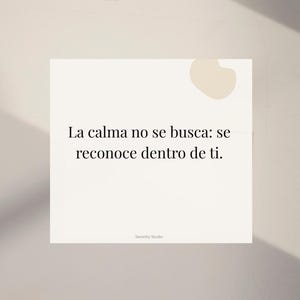 Op de afbeelding: Een vierkante, gebroken witte kaart met de tekst "La calma no se busca: se reconoce dentro de ti." in het zwart. De woorden zijn gecentreerd op de kaart. De kaart heeft een kleine, lichtbruine vorm in de rechterbovenhoek. De woorden "Serenity Studio" staan onderaan.