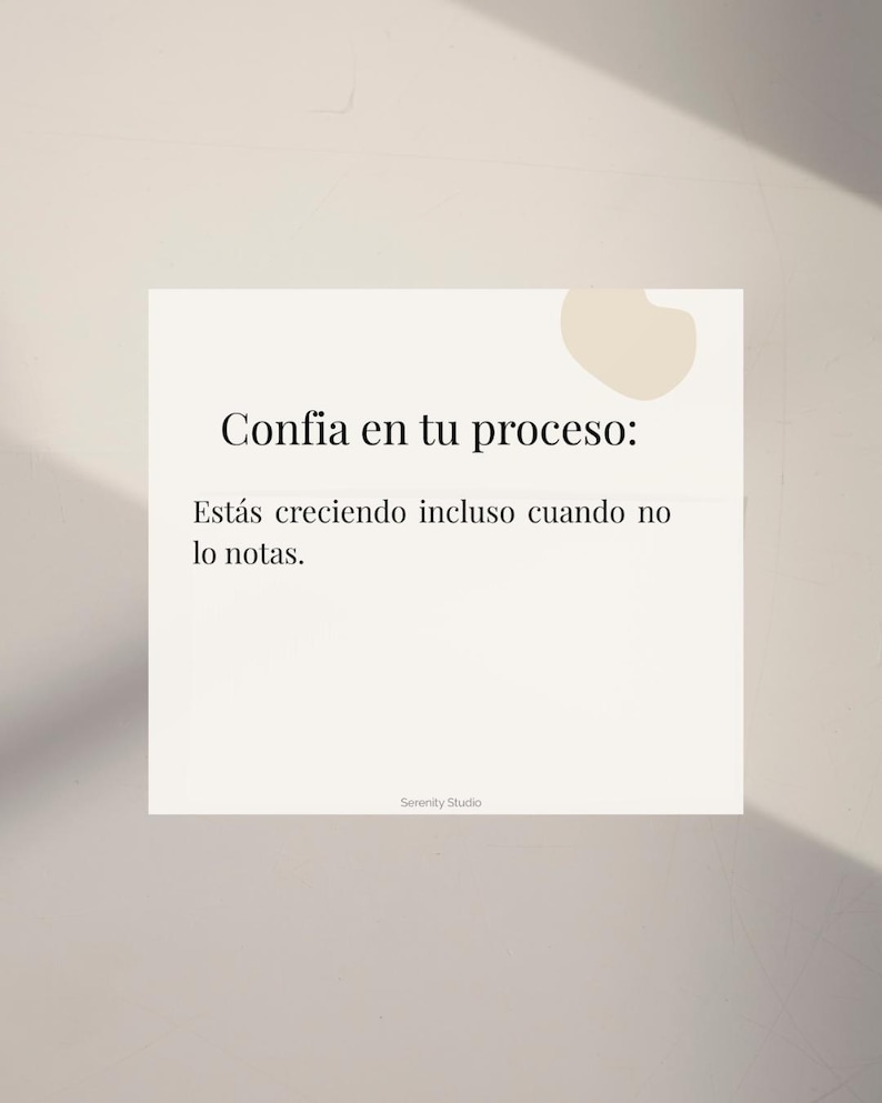 Op de afbeelding: Een vierkante, gebroken witte kaart met de tekst "Confia en tu proceso: Est&aacute;s creciendo incluso cuando no lo notas." in het zwart. De kaart bevat ook de tekst "Serenity Studio" onderaan. Een beige vorm bevindt zich in de rechterbovenhoek.