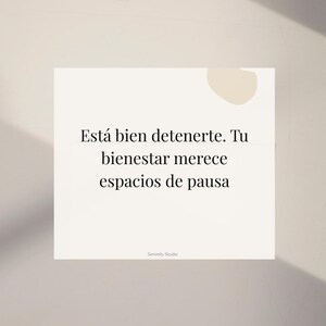 Op de afbeelding: Een witte vierkante kaart met de tekst "Est&aacute; bien detenerte. Tu bienestar merece espacios de pausa" in het zwart. De kaart heeft een minimalistisch ontwerp met een beige achtergrond en een kleine beige vorm in de rechterbovenhoek. De woorden "Serenity Studio" staan onderaan.
