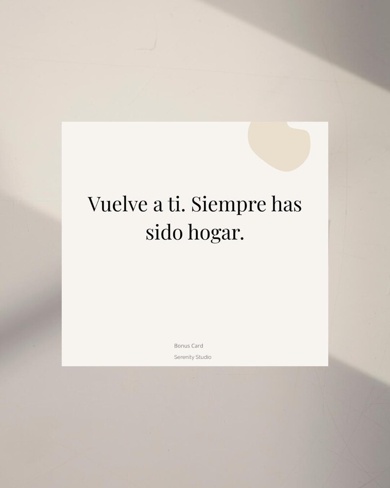 Op de afbeelding: Een vierkante, gebroken witte kaart met de Spaanse tekst "Vuelve a ti. Siempre has sido hogar." in het zwart. De woorden "Bonus Card" en "Serenity Studio" staan eronder. Een lichtbeige vorm bevindt zich in de rechterbovenhoek.