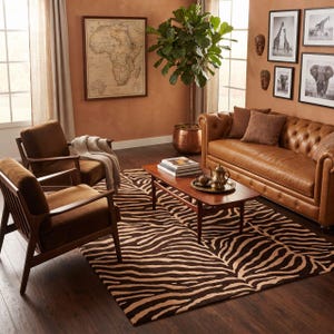 May include: A living room featuring a brown leather tufted sofa, two brown upholstered armchairs with wooden frames, and a rectangular wooden coffee table. A large area rug with a brown and tan zebra stripe pattern covers the dark wood floor.
