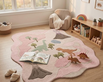 May include: A large, irregularly shaped area rug in shades of pink and beige, featuring a tufted dinosaur landscape with volcanoes, trees, and various dinosaur figures. An open book titled My First Dinosaur Encyclopedia rests on the rug surface.