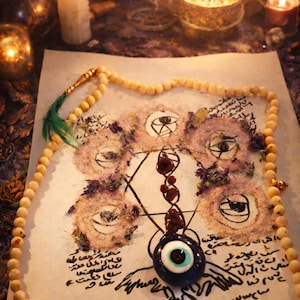 May include: A mystical arrangement featuring a central drawing with eye symbols, surrounded by a beaded necklace and a blue eye charm. Lit candles and incense create a spiritual ambiance. The drawing includes script.