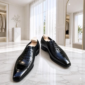 Peut inclure: Une paire de chaussures oxford en cuir noir présentant une texture gaufrée façon crocodile brillante sur l'empeigne et le quartier, un bout carré, des lacets noirs et des embauchoirs en bois clair insérés à l'intérieur de chaque chaussure.