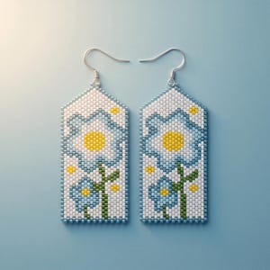 Peut inclure: Une paire de boucles d'oreilles rectangulaires en perles avec un fond blanc et un motif de fleurs bleu clair et jaune. Chaque boucle présente une tige verte et de petits accents jaunes, terminées par des crochets en métal argenté.