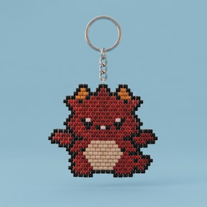 May include: A keychain featuring a pixelated bear character crafted from small square beads. The bear is primarily dark red with black outlines, orange ear accents, and a light beige belly. It is attached to a silver metal split ring by a short chain.