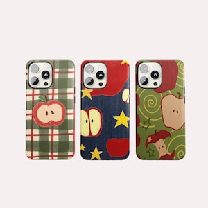 Puede incluir: Tres fundas para teléfono con diseños de manzanas. Una funda tiene un patrón de cuadros verdes y rojos con una ilustración de manzana roja. Otra tiene una parte superior roja y un fondo de mezclilla azul con estrellas amarillas e ilustraciones de manzanas. La tercera funda tiene un fondo verde con ilustraciones de manzanas.