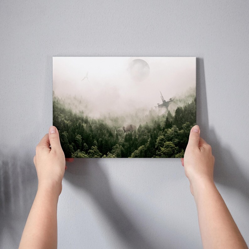 May include: A rectangular wall art print featuring a dense green forest landscape shrouded in thick white fog. A large, pale circular orb hangs in the sky above the treetops, with a faint, angular structure visible emerging from the mist.