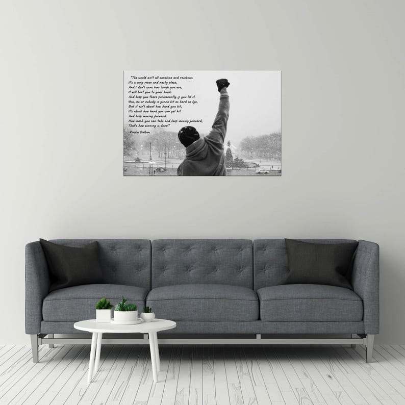 May include: Black and white print of a person with their fist raised in the air, inspired by the movie Rocky. The image includes a quote from the movie. The person is wearing a hooded sweatshirt and a hat. The background shows a snowy outdoor scene.